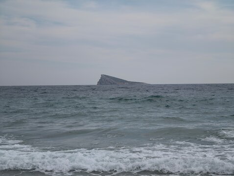 isolated triangular islet amidst stormy waters, secluded triangular rock surrounded by turbulent