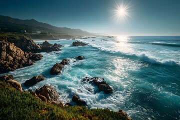 Obraz premium Picturesque coastline with turquoise waves lapping against a rocky shore and a bright sunburst reflecting off the water near green grass.