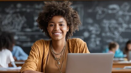 A young woman smiles confidently while sitting at a desk in a classroom, surrounded by fellow students and a chalkboard filled with mathematical equations