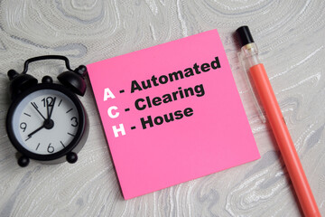 Concept of ACH - Automated Clearing House write on sticky notes isolated on Wooden Table. © syahrir
