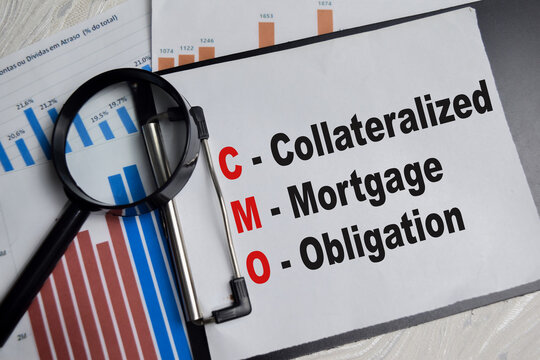 Concept of CMO - Collateralized Mortgage Obligation write on clipboard with financial graphs isolated on Wooden Table.