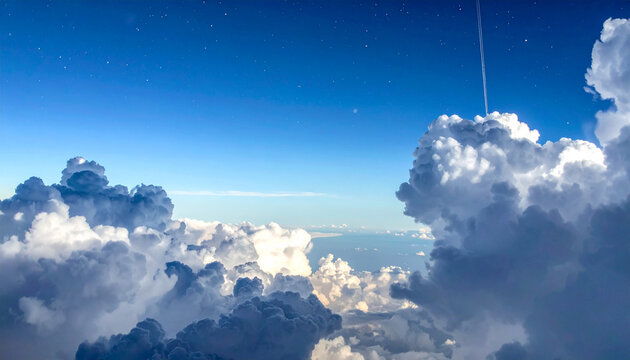 Airplane view of fluffy white clouds against a deep blue sky with stars and contrail aerial view