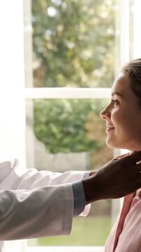 Doctor Examines Patient's Thyroid Gland with Light Pink Shirt in Bright Room near Window Thyroid Examination Palpation Diagnosis Healthcare Checkup for Goiter Nodules and Thyroiditis Concept