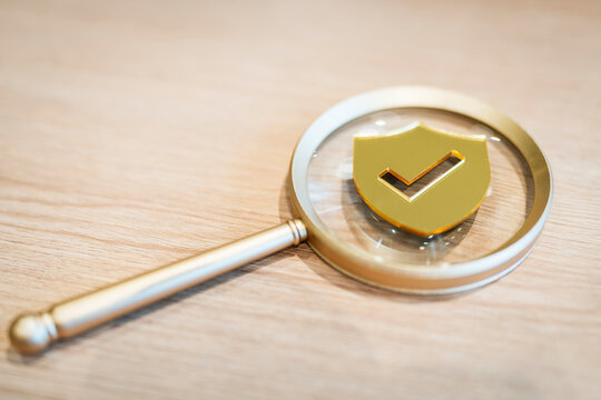 Magnifying glass focusing on golden shield with check mark, symbolizing data security, trust verification, risk assessment, privacy audit, cybersecurity, and online protection concepts.