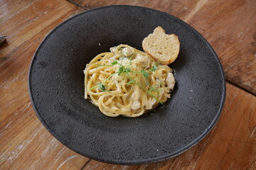 Carbonara, a classic Italian pasta dish topped with a creamy and savory cheese sauce, is served on the table.