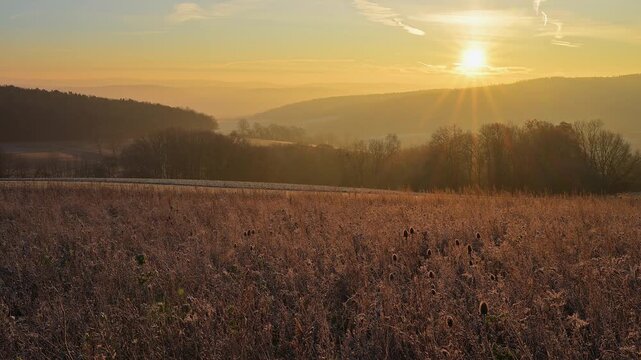 Gefrorenes Feld bei Sonnenaufgang, strahlende Sonne &uuml;ber der Landschaft, die die Natur erhellt, Seckmauern, L&uuml;tzelbach, Maintal, Odenwald, Hessen, Deutschland