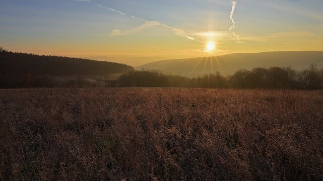 Gefrorenes Feld bei Sonnenaufgang, strahlende Sonne &uuml;ber der Landschaft, die die Natur erhellt, Seckmauern, L&uuml;tzelbach, Maintal, Odenwald, Hessen, Deutschland