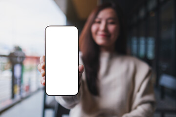 Mockup image of a woman holding and showing at a mobile phone with blank white screen