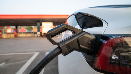 EV charger handle plugged in connect to electric car outdoor station