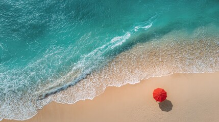 A striking red umbrella stands alone on a golden sandy beach. Gentle turquoise waves lap at the shore under a clear blue sky creating a perfect spot for relaxation.