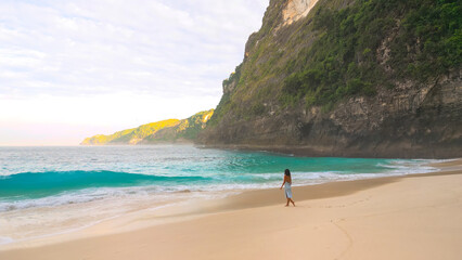Woman Walking On Kelingking Beach Bali With Turquoise Waves And Cliffs