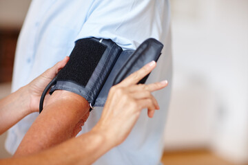 Nurse, hands and blood pressure with machine for healthcare exam, hypertension or test in home. Caregiver, doctor or monitoring heart rate with patient or arm strap for health evaluation in house