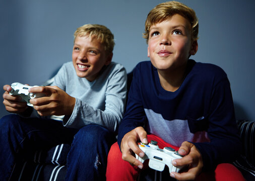 Video game, competition or siblings on sofa with controller, contest or playful challenge in multiplayer. Low angle, children or family in home with tech, bonding or console match in virtual activity - Powered by Adobe