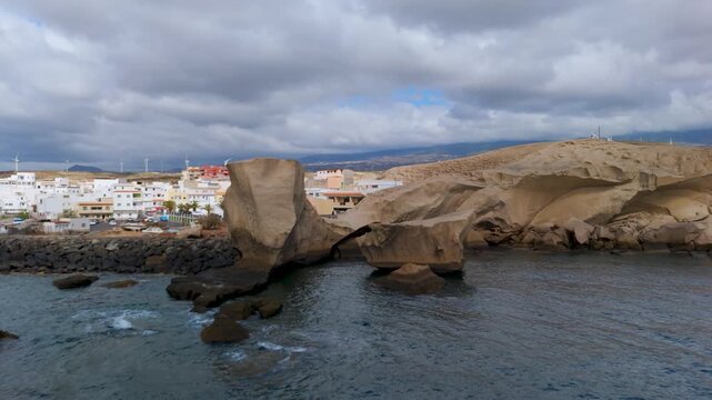 Low aerial drone flight over the Atlantic Ocean approaching the iconic volcanic rock formation near the fishing port of San Miguel de Tajao, Tenerife, Spain.