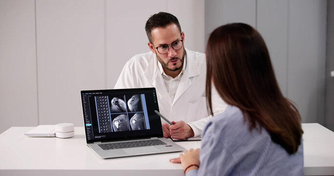 Doctor Explaining Shoulder X-ray To Patient In Clinic With Computer - Powered by Adobe
