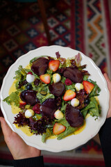 salad of eggs, meat, strawberries, raspberries in your hands