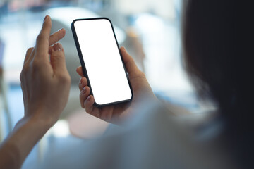 Mockup blank white screen mobile phone. Woman hand holding, using smartphone at coffee shop, template for mobile app design, social media marketing, close up