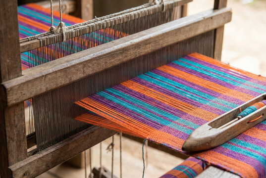 Close-up of a traditional wooden handloom weaving machine with colorful cotton threads and a shuttle. - Powered by Adobe