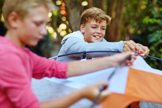 Children, camping and pitching tent outdoor for travel, vacation adventure and learning skills. Kids, friends and help setup equipment for shelter protection, prepare campsite and holiday in nature