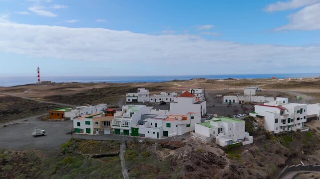 High aerial drone view flying over the white housing settlement on the arid, volcanic coast of Playa Grande, Punta de Abona, Tenerife, Canary Islands, Spain.