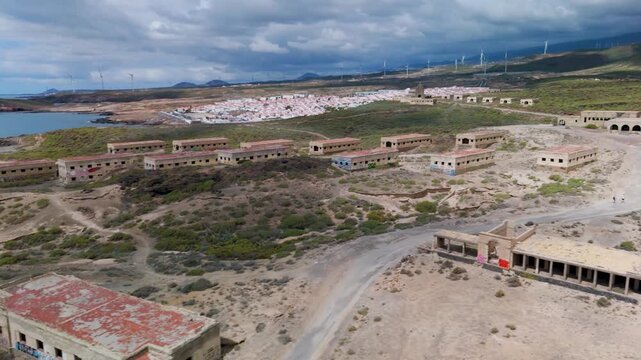 Aerial drone pan across the eerie, derelict residential blocks of the abandoned Abades Leper Colony and Sanatorium ruins in Tenerife, Canary Islands, Spain.
