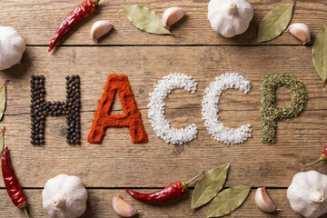 Top view of HACCP acronym spelled with natural spices and ingredients on wooden table for food safety culinary concept and gastronomy regulation symbol