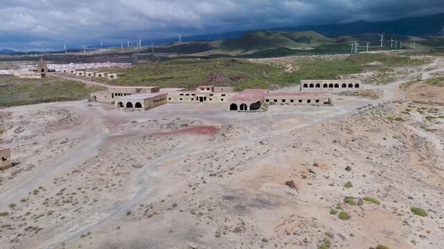 High angle aerial drone flight over the sprawling, abandoned Abades Leper Colony and Sanatorium complex on the arid coast of Tenerife, Canary Islands, Spain.