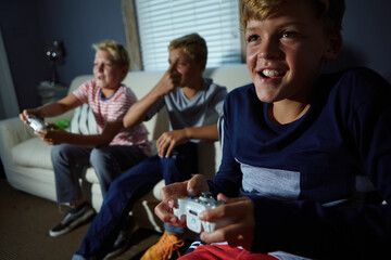 Children, controller and video game with boy on sofa in living room of home together for fun. Console gaming, friends and entertainment with group of happy kids in apartment for online level up
