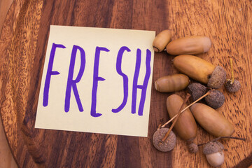 Fresh acorns on wooden background - natural seeds concept