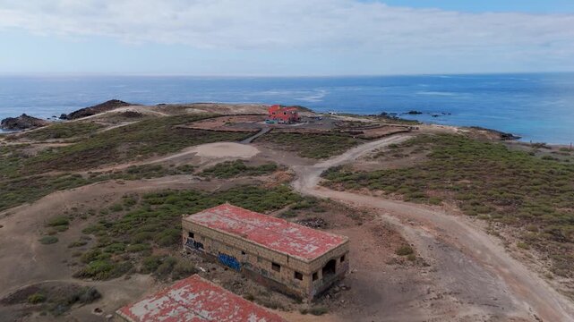 Aerial view panning across the eerie, derelict complex of the Sanatorio de Abades, the infamous abandoned Leper Colony ruins on the coast of Tenerife, Canary Islands.