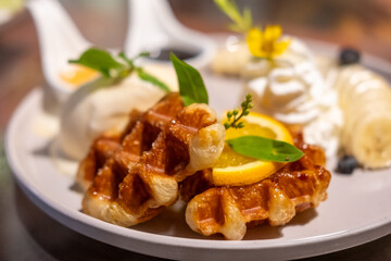 Waffle with vanilla ice cream served with sliced banana , whipped cream and sauce.