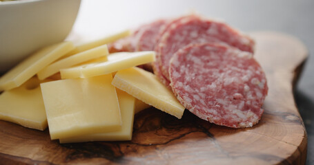 green olives, cheese and salami on olive wood board
