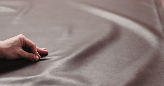 man hand checking brown leather piece closeup