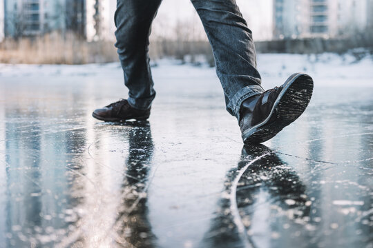 Fototapeta Boots standing on icy ground, illustrating the danger of slipping on a frozen, slippery winter surface. man walks cautiously along an icy street on a winter day for fear of slipping and falling.