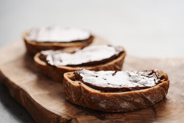 Ciabatta slices with chocolate spread on olive wood board