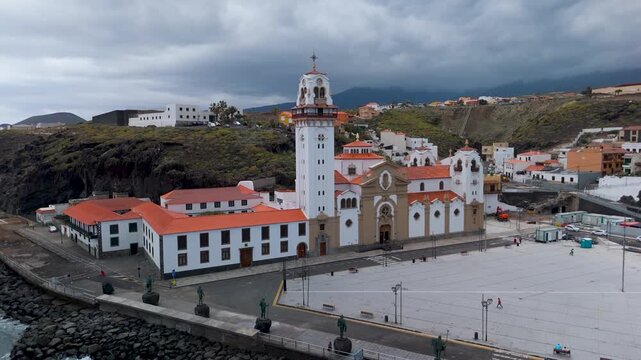 Aerial circling drone shot of the Basilica of Our Lady of Candelaria, facing the Atlantic Ocean in the colorful coastal town of Candelaria, Tenerife, Spain.