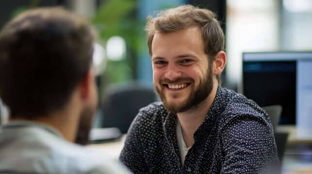 Two men in a casual office setting, engaged in a conversation.