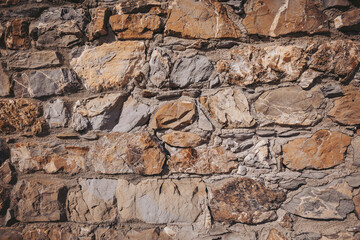 Detailed texture of a natural stone wall showcasing various shapes and colors in a rustic setting during daylight