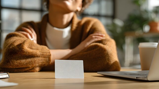Focused businesswoman with blank business card and laptop on modern office desk, thoughtful concept - Powered by Adobe