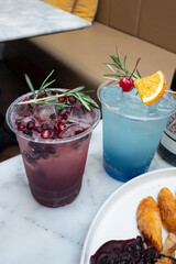 Vibrant Drinks: Two Refreshing Cocktails. Each drink is carefully crafted with garnishes like rosemary and cherries