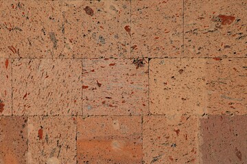 Background, texture of a wall decorated with tiles made of natural pink tuff stone