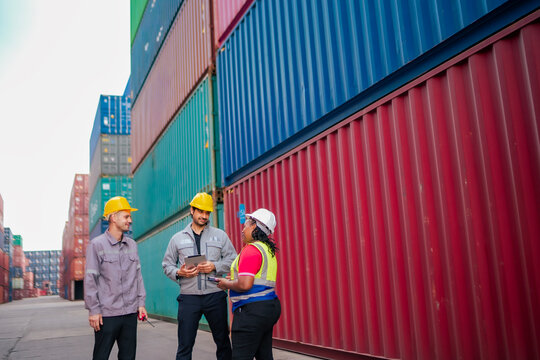 Team members stand in front of stacked containers as they receive instructions for handling inbound and outbound cargo. The discussion emphasizes safe workflow practices, communication in logistics.