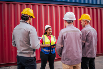 A cargo manager talks to on-site staff about transport coordination while ensuring proper safety procedures and documentation handling in the container yard.