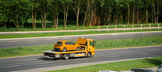 Tow truck hauling yellow car down road