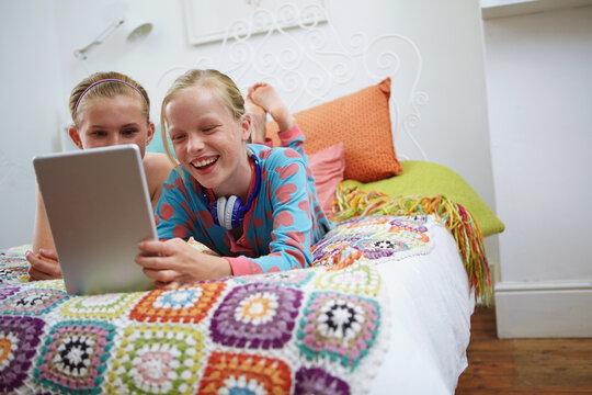 Laugh, teen friends and tablet on bed for funny online post, social media meme or chill at sleepover. Happy, girls or relax with digital app in bedroom for streaming, bonding or weekend break in home