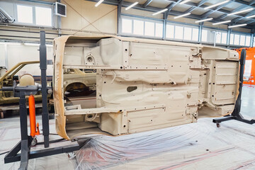 Specialist spraying anti rust sealant into the hidden chassis cavities. Protection against corrosion and internal body element sealing in a professional auto service shop