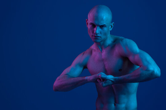 Strong man posing with confidence, showcasing a bold attitude and intense expression. The dramatic lighting emphasizes muscular features and highlights his determination. - Powered by Adobe