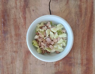 homemade pet meal prepared with care, featuring chopped cucumber, chicken liver, gizzard, and pork, served in a simple bowl on a wooden table.