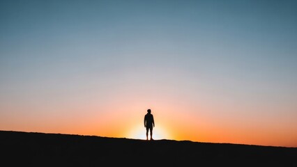 Silhouette Of Solitary Figure Standing At Sunset Horizon