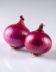 Two vibrant red onions on a reflective white surface, studio shot